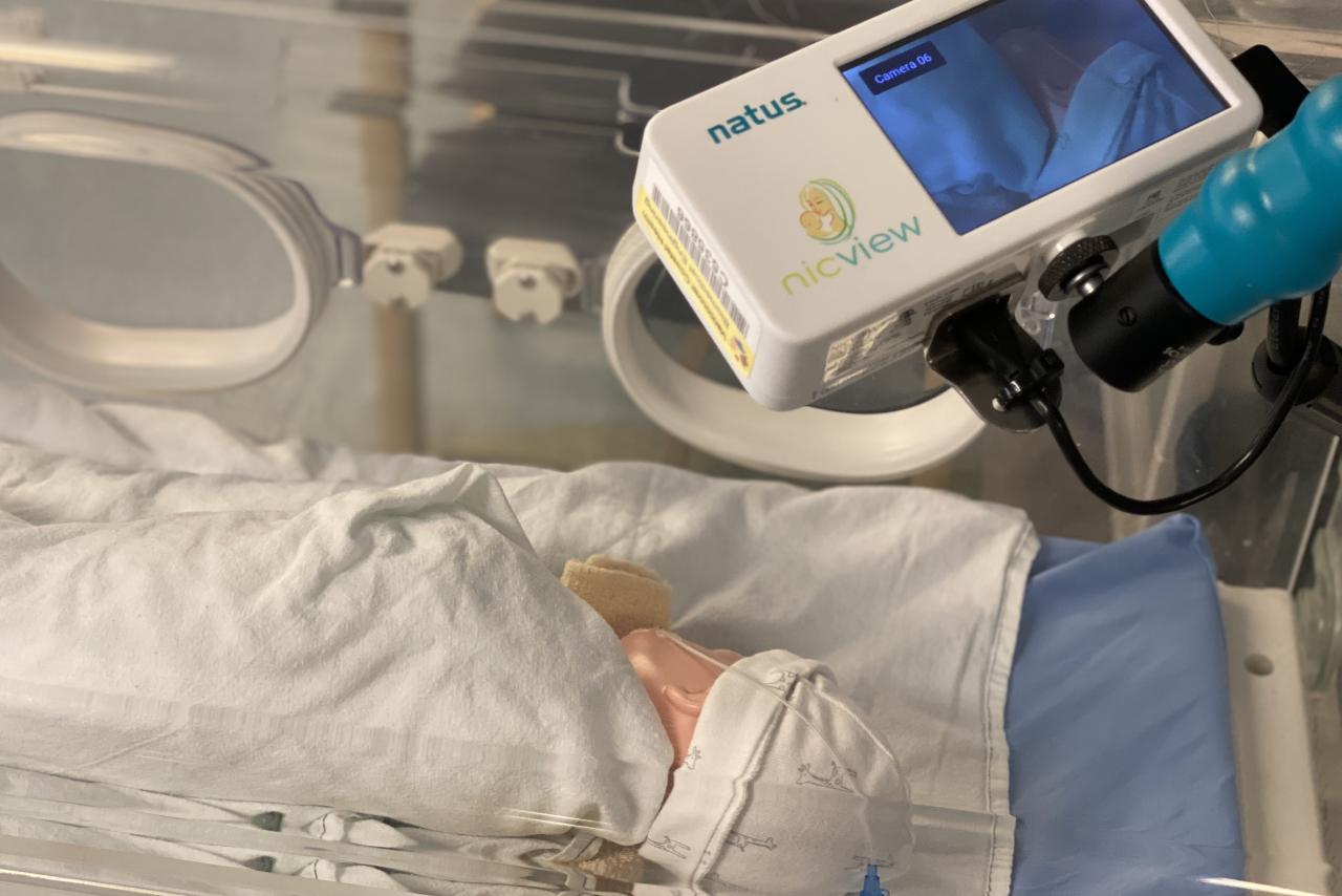Person holding Richmond Neonatal Intensive Care Unit (NICU) camera over a mannequin baby.