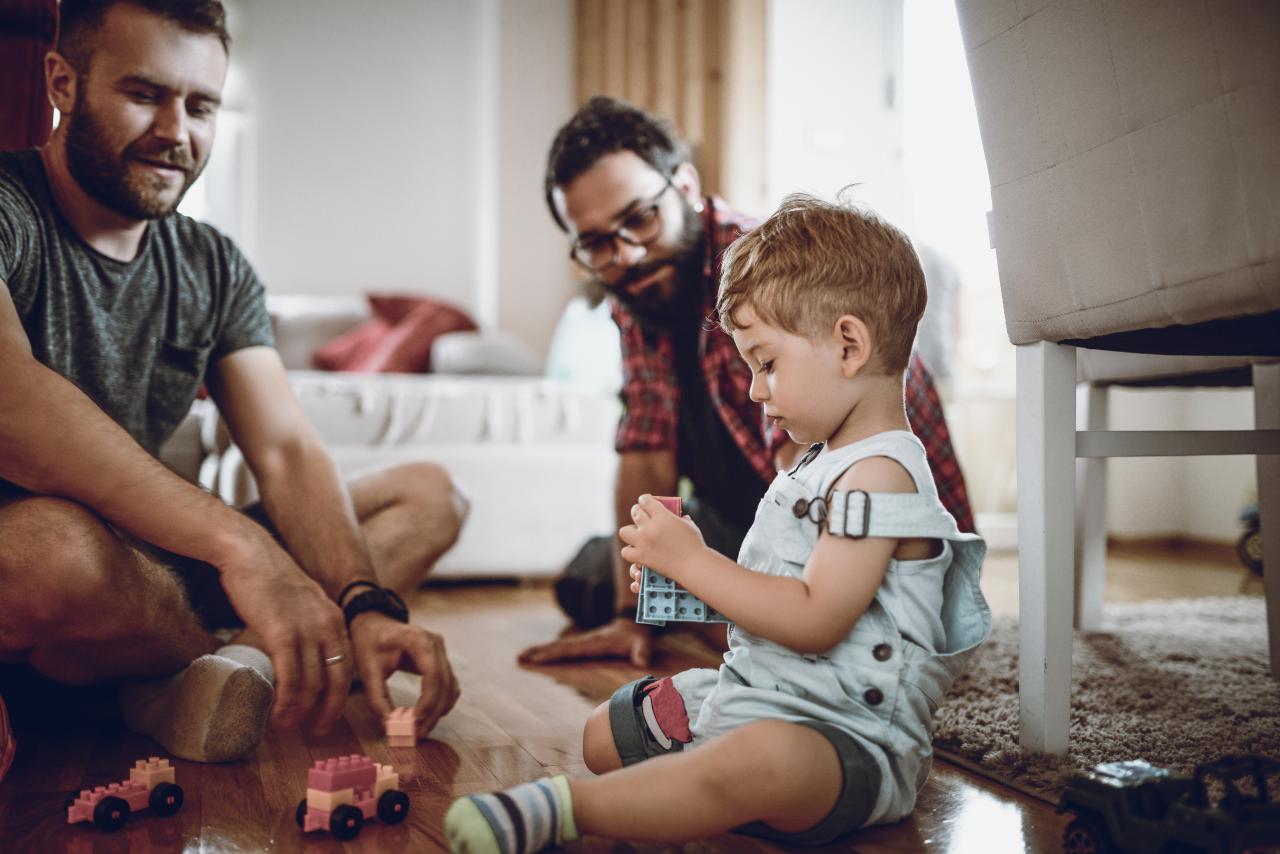 A toddler and their parents playing with toys on the ground.