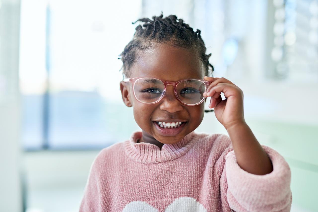 Young child smiling wearing glasses in an optometrist's office
