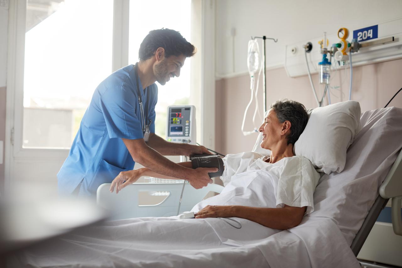 Nurse taking a patients blood pressure in bed