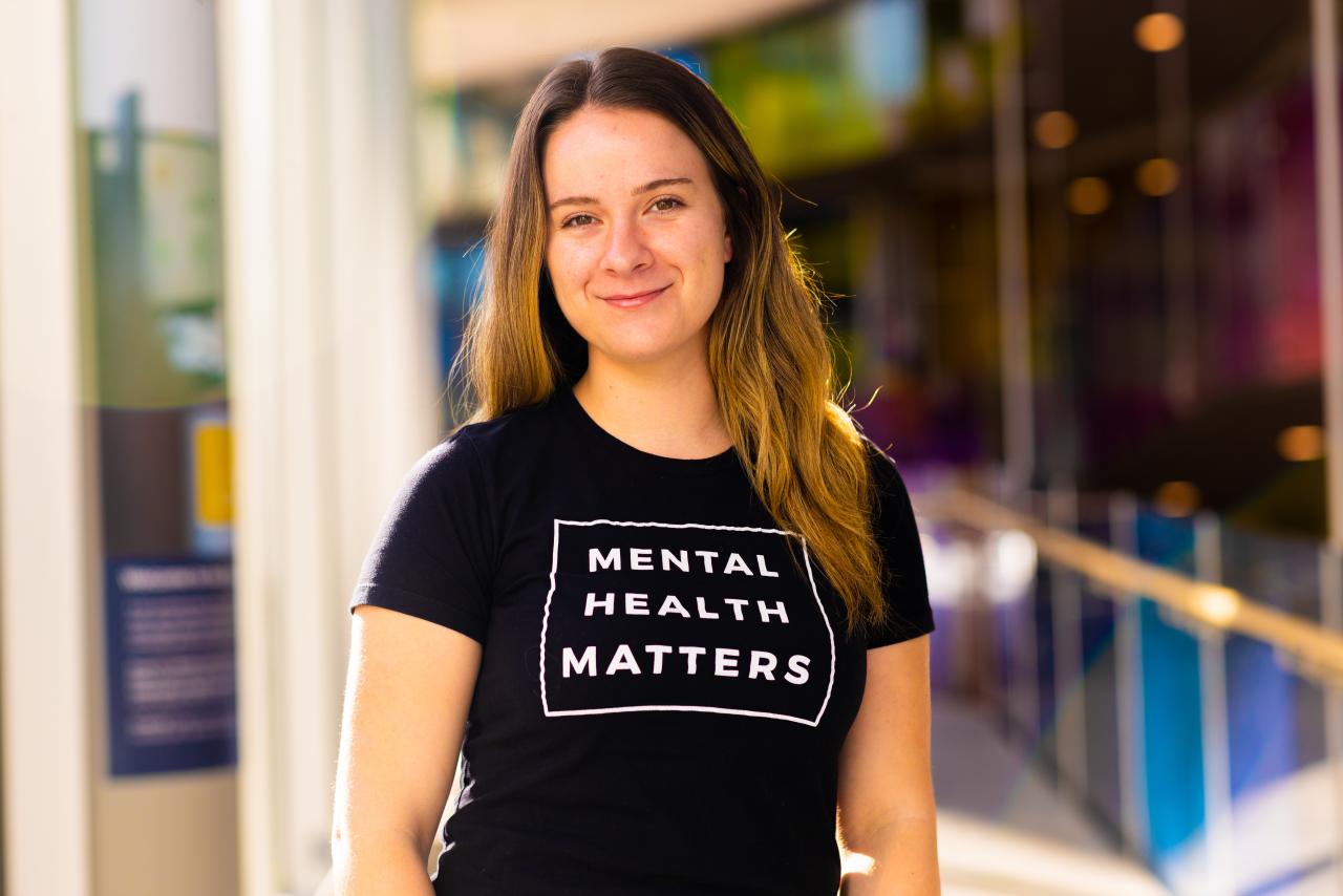 Kenna Balogh is facing the camera and wearing a t-shirt that says mental health matters