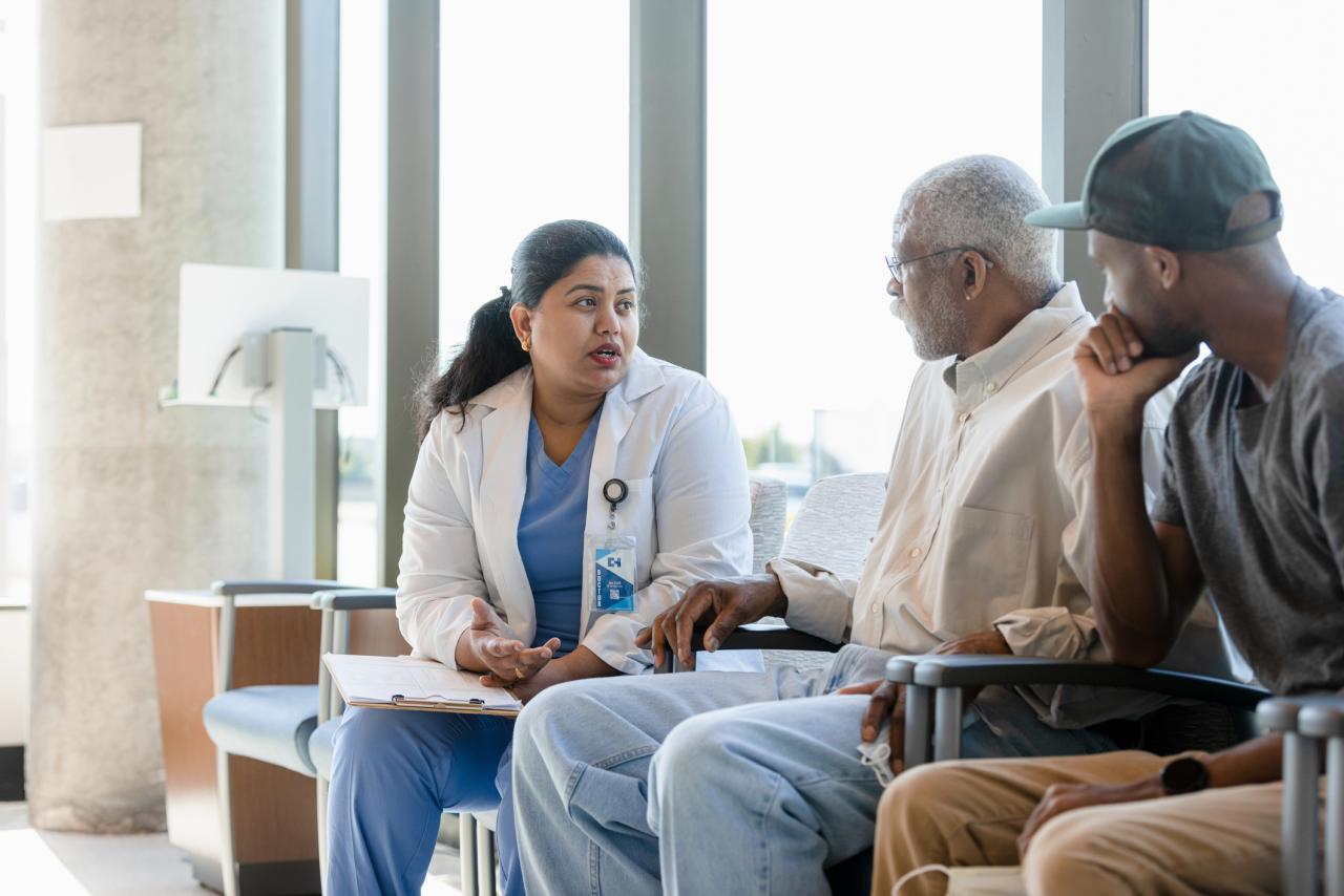 The senior adult and his young adult child listen as the female doctor explains information