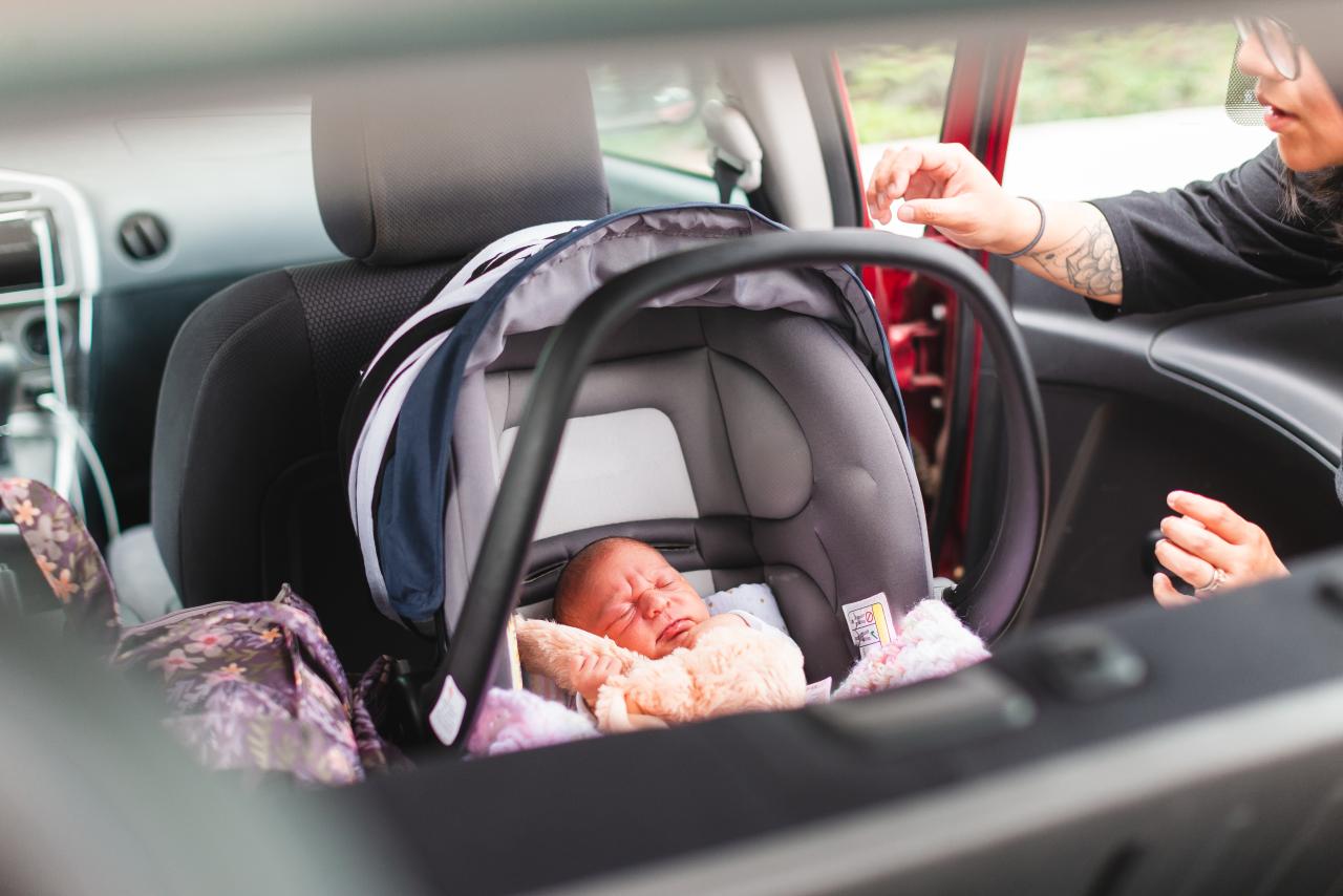Mother Buckling Her Newborn Baby Into Car Seat