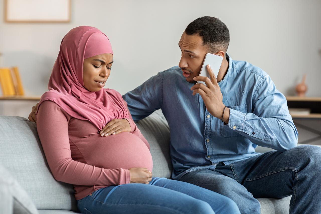 Man calling doctor while wife has prenatal contractions