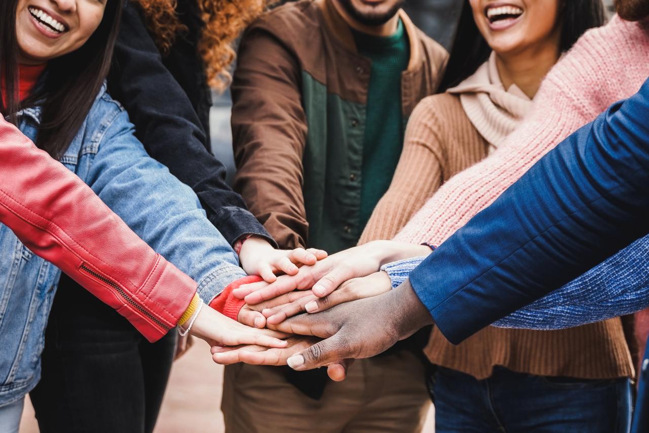 Happy group of people stacking hands together