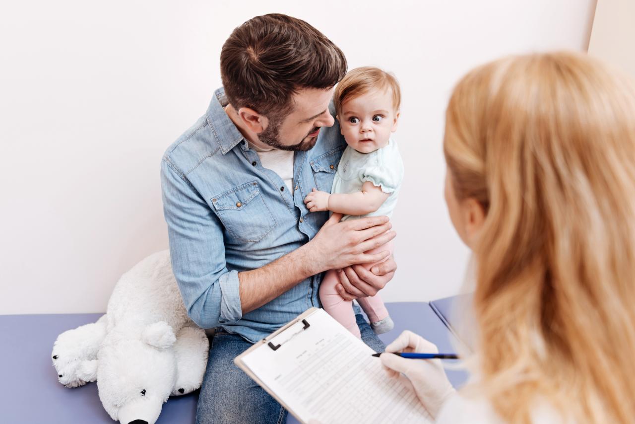 A person holding a baby with a doctor holding a clipboard