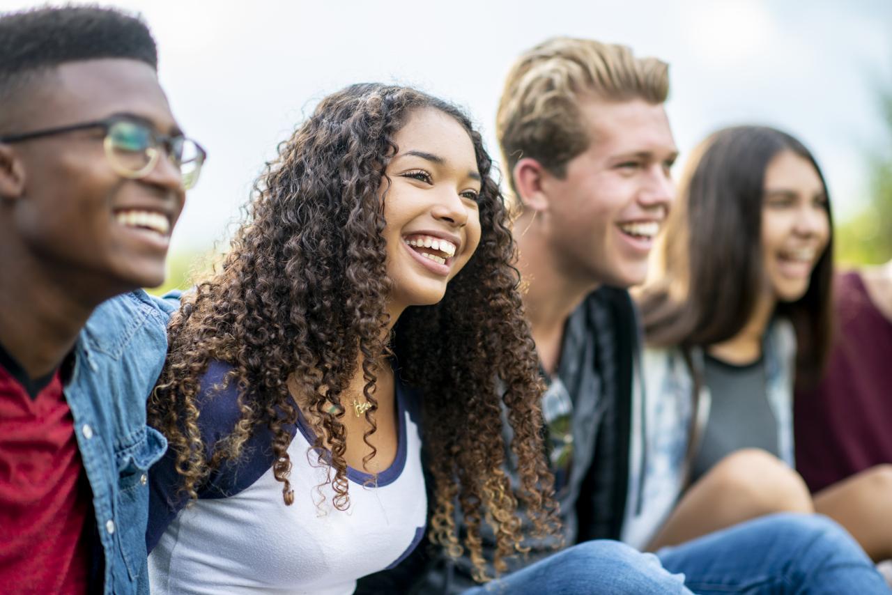 Four youth smiling for a picture outside.