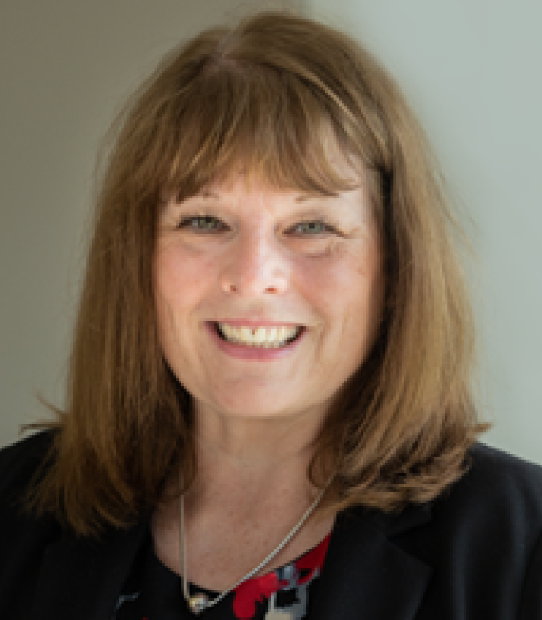 Portrait of Gail Malenstyn indoors. She is wearing a floral shirt and black sweater