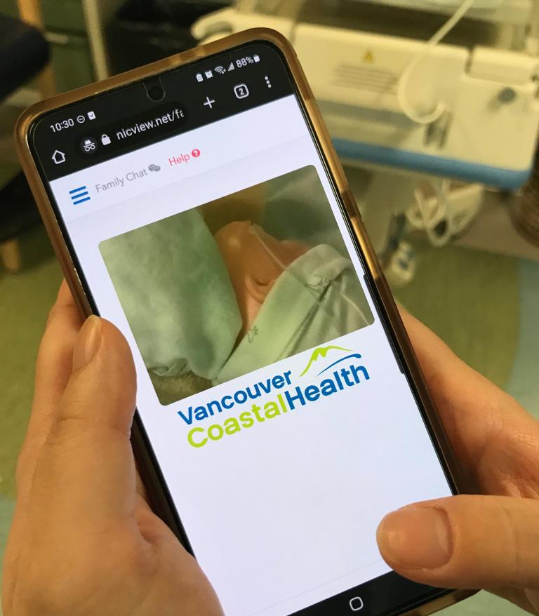 Parent on their phone watching webcam of baby.