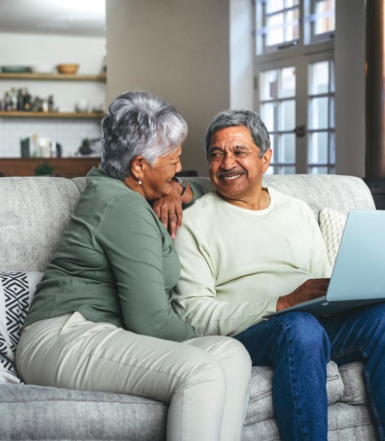 a senior couple using a laptop on the sofa at home