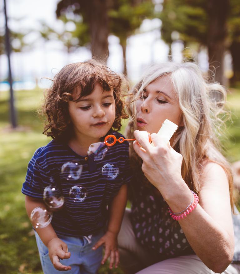 Grandmother and grandson blowing bubbles at a park
