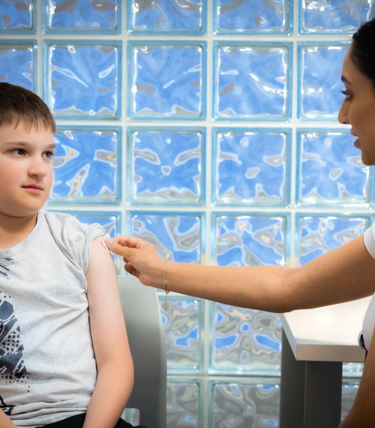 Young person sitting with VCH staff member for their immunizations.