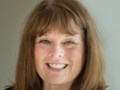 Portrait of Gail Malenstyn indoors.  She is wearing a floral shirt and black sweater
