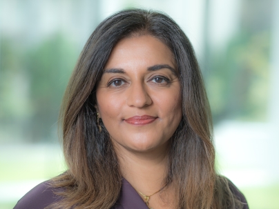 A portrait of Yasmin Jetha indoors.  She is wearing a purple shirt